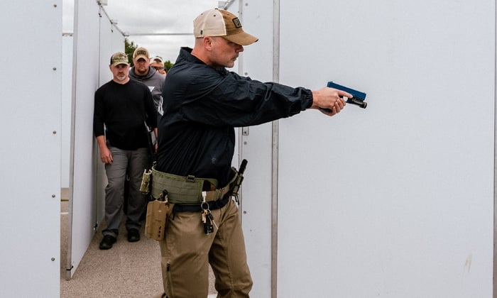 Tactical team conducting CQB training inside a modular shoot house with portable panel walls.